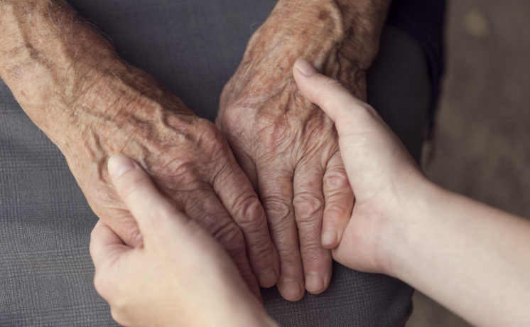 Old and young person holding hands. Elderly care and respect, selective focus